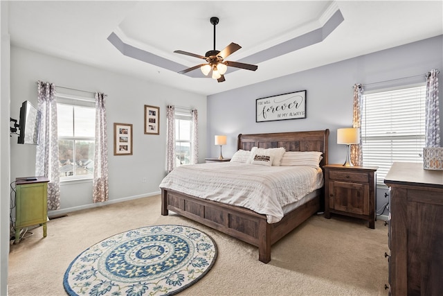 carpeted bedroom featuring a raised ceiling, multiple windows, and ceiling fan