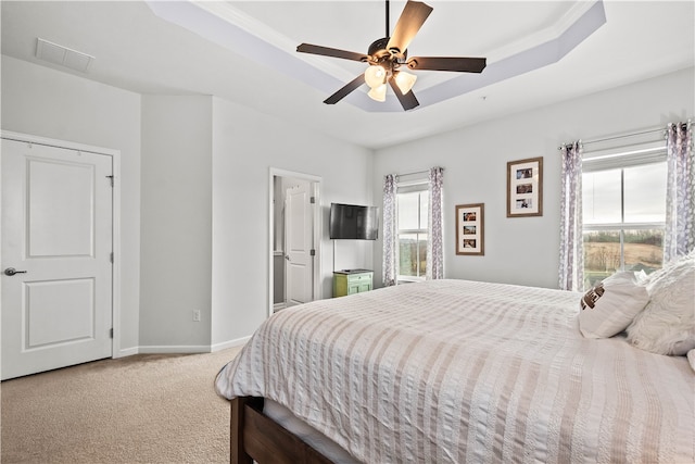 carpeted bedroom featuring a tray ceiling and ceiling fan