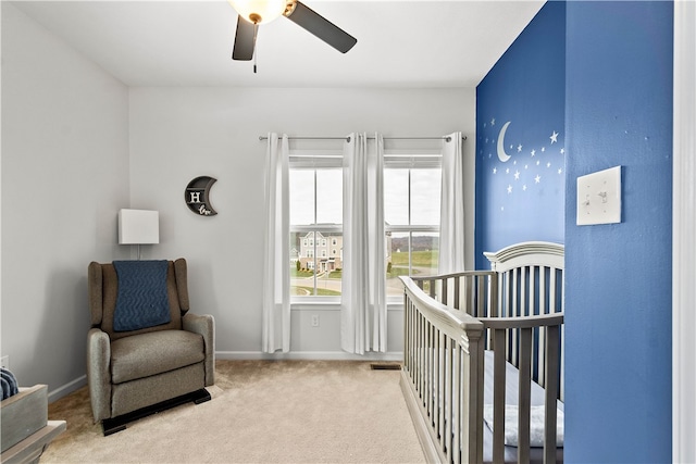 carpeted bedroom with ceiling fan and a crib