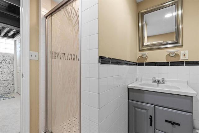 bathroom featuring a shower with door, vanity, and tile walls