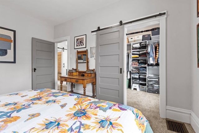 carpeted bedroom featuring a barn door and a closet