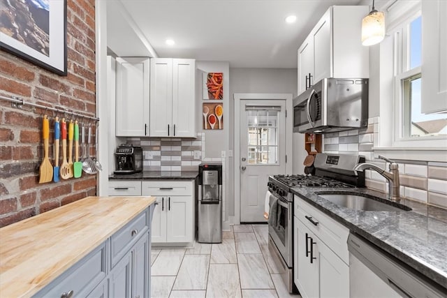 kitchen featuring butcher block counters, plenty of natural light, white cabinets, and appliances with stainless steel finishes