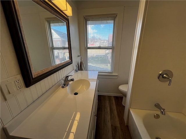 bathroom with toilet, plenty of natural light, vanity, and hardwood / wood-style flooring