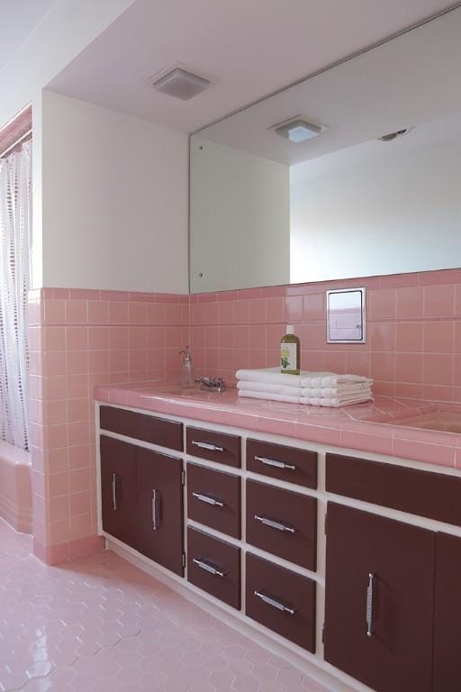 bathroom featuring tile patterned floors, shower / tub combo, vanity, and tile walls