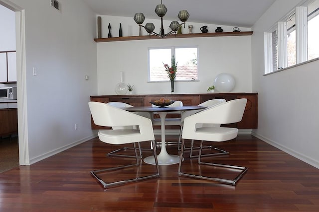 dining room with dark wood-type flooring, vaulted ceiling, and a notable chandelier