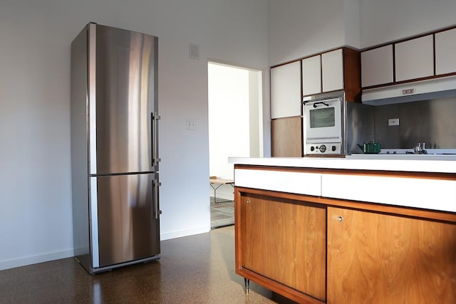 kitchen featuring white oven, stainless steel refrigerator, black stovetop, and white cabinets