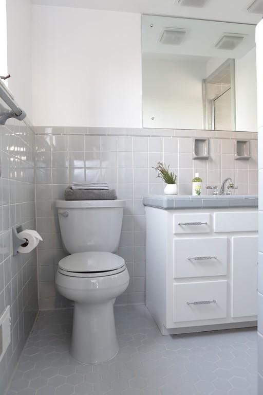 bathroom with tile patterned floors, vanity, toilet, and tile walls