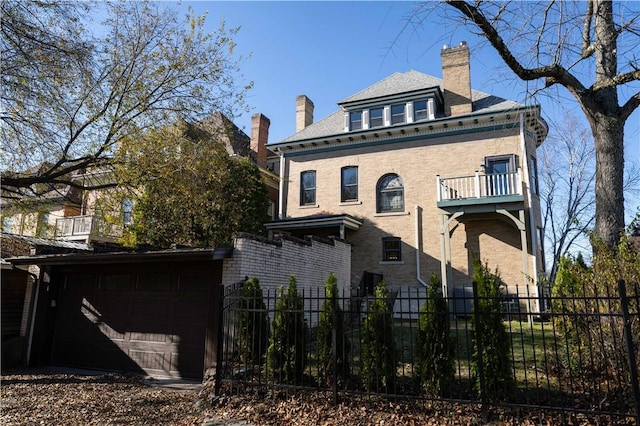 rear view of house featuring a balcony and a garage