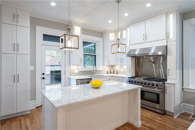 kitchen with white cabinets, appliances with stainless steel finishes, a kitchen island, and range hood