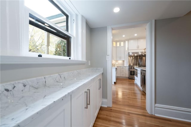 bar featuring tasteful backsplash, white cabinetry, and light hardwood / wood-style flooring