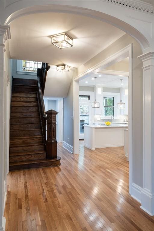 stairs featuring decorative columns and hardwood / wood-style flooring