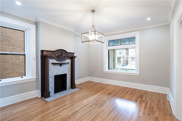 unfurnished living room with an inviting chandelier, light hardwood / wood-style flooring, and ornamental molding