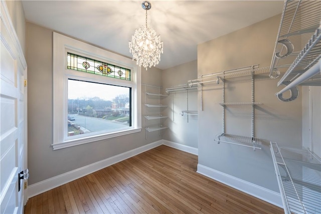 spacious closet with wood-type flooring and a notable chandelier