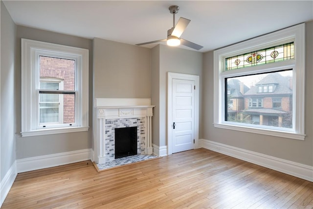 unfurnished living room featuring a fireplace, a wealth of natural light, light hardwood / wood-style flooring, and ceiling fan