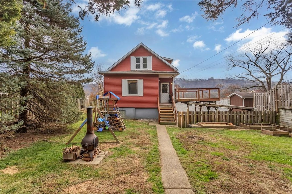 back of house with a deck and a lawn