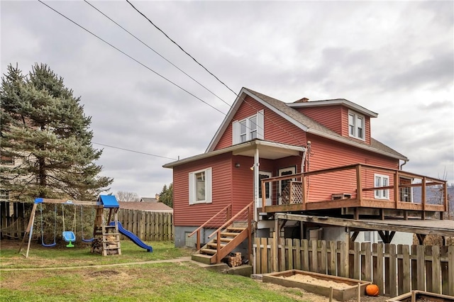 back of house with a lawn, a deck, and a playground