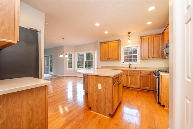 kitchen featuring a center island, hanging light fixtures, light wood-type flooring, a notable chandelier, and stainless steel appliances