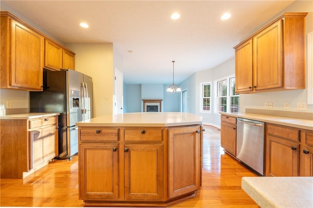 kitchen featuring a center island, hanging light fixtures, light hardwood / wood-style flooring, appliances with stainless steel finishes, and a chandelier