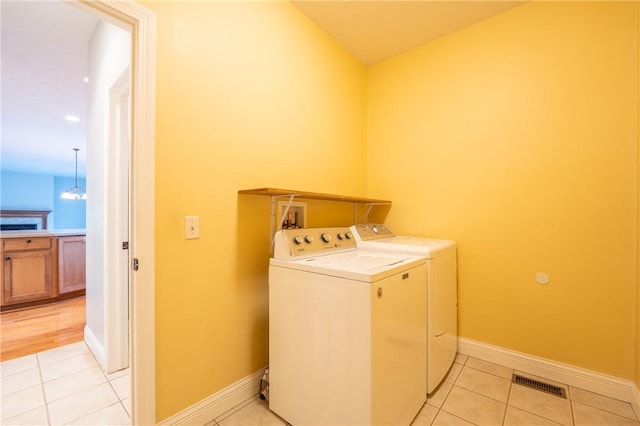 washroom with washing machine and dryer, light tile patterned floors, and a notable chandelier