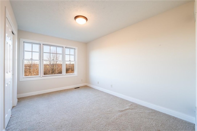 carpeted empty room featuring a textured ceiling