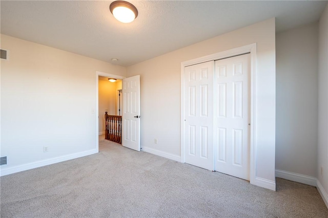 unfurnished bedroom with light carpet, a closet, and a textured ceiling