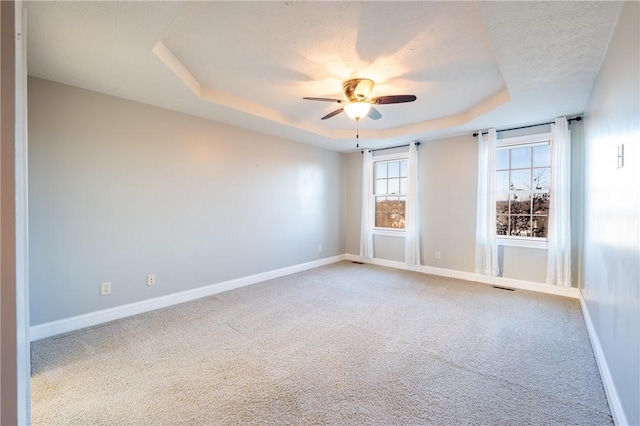 unfurnished room featuring carpet flooring, ceiling fan, a raised ceiling, and a textured ceiling