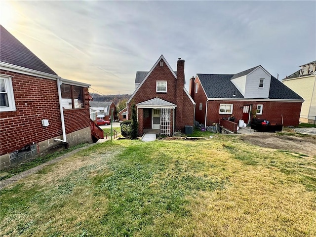 rear view of property featuring central AC unit and a lawn