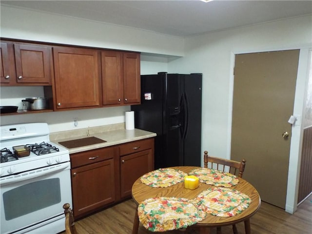 kitchen with black fridge with ice dispenser, white gas stove, and hardwood / wood-style floors