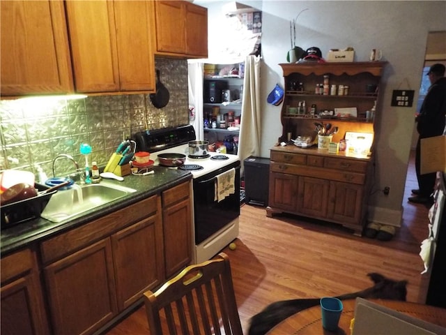 409 1st St, East Bethlehem, PA 15368 - kitchen with electric range, decorative backsplash, a sink, light wood-style floors, and brown cabinets