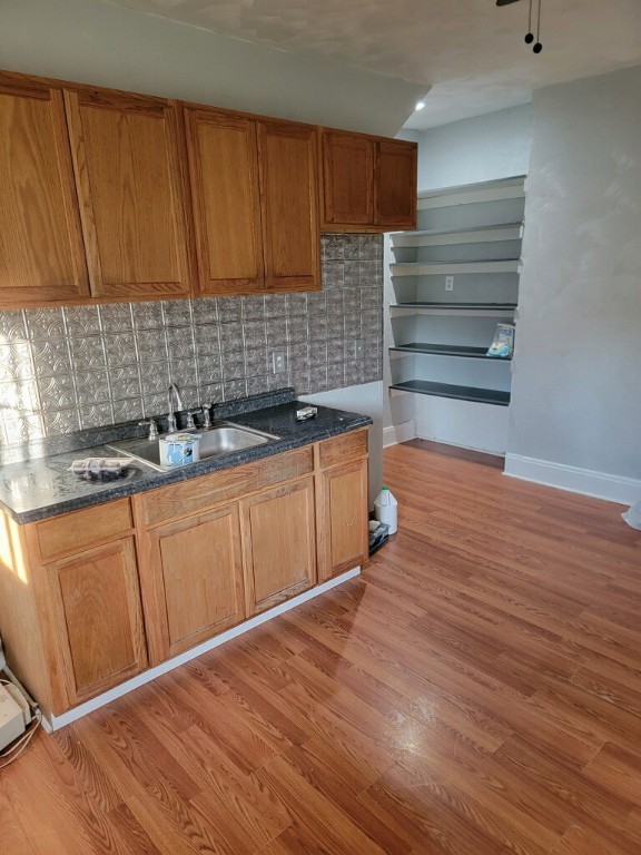 kitchen with tasteful backsplash, sink, and light hardwood / wood-style flooring