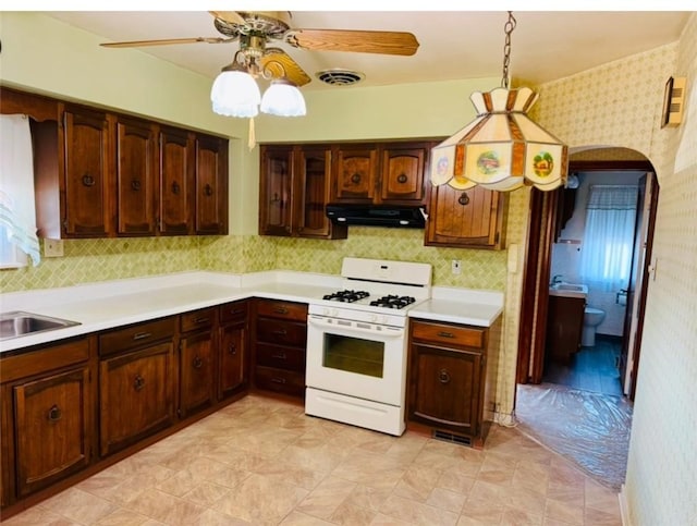 kitchen with dark brown cabinets, ceiling fan, white range with gas cooktop, sink, and decorative light fixtures