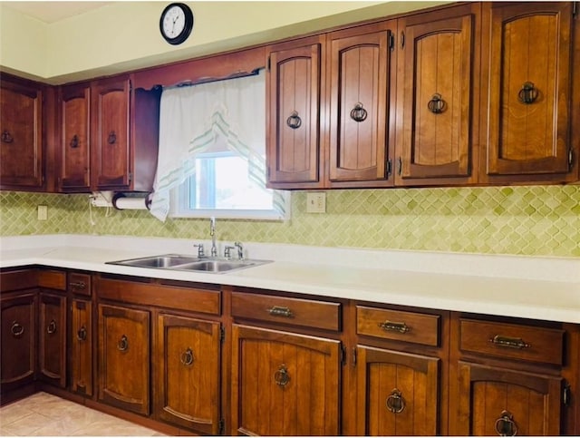 kitchen featuring backsplash, light tile patterned floors, and sink