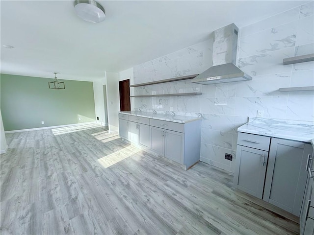 kitchen featuring gray cabinetry, light hardwood / wood-style flooring, and wall chimney range hood