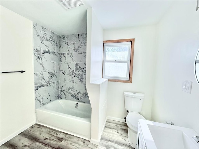 full bathroom featuring hardwood / wood-style floors, vanity, toilet, and tiled shower / bath