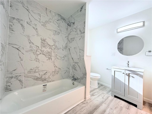 full bathroom featuring vanity, tiled shower / bath combo, hardwood / wood-style flooring, and toilet