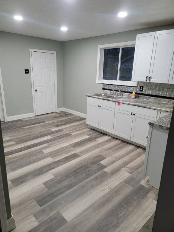 kitchen with white cabinetry, sink, and light hardwood / wood-style floors