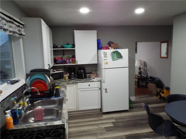 kitchen with white cabinets, white fridge, sink, and hardwood / wood-style flooring