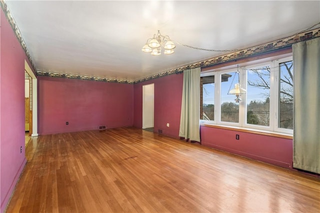 spare room featuring a chandelier and hardwood / wood-style flooring