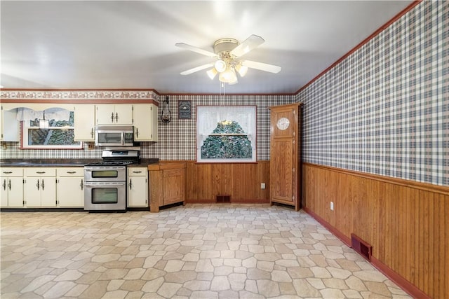 kitchen featuring decorative backsplash, ceiling fan, stainless steel appliances, and wooden walls