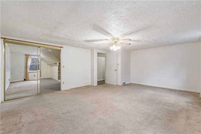 empty room with light carpet, a textured ceiling, and ceiling fan