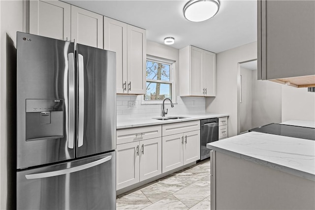 kitchen featuring light stone countertops, backsplash, stainless steel appliances, sink, and white cabinetry