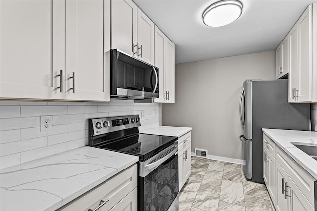 kitchen featuring light stone countertops, backsplash, white cabinetry, and stainless steel appliances