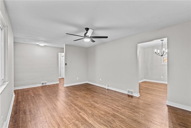 empty room with hardwood / wood-style floors and ceiling fan with notable chandelier