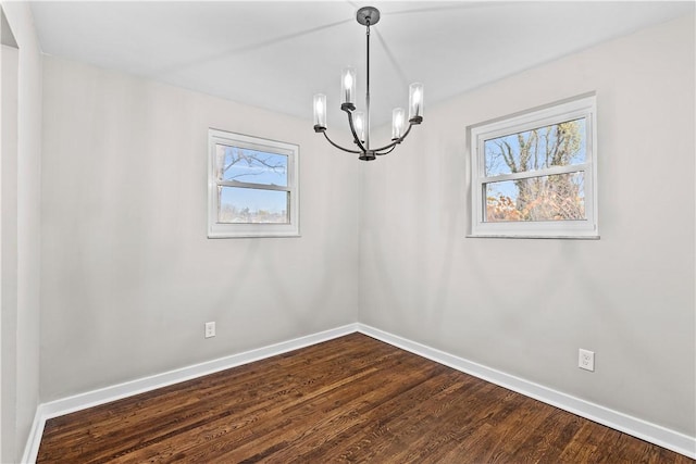 spare room with hardwood / wood-style floors, plenty of natural light, and a notable chandelier