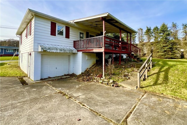 rear view of property with a garage, a deck, and a lawn