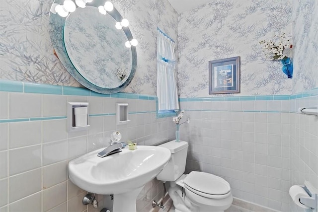 bathroom featuring sink, toilet, and tile walls