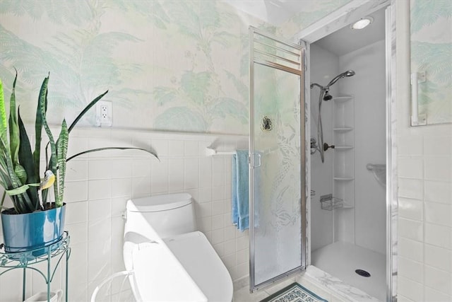 bathroom featuring toilet, an enclosed shower, and tile walls