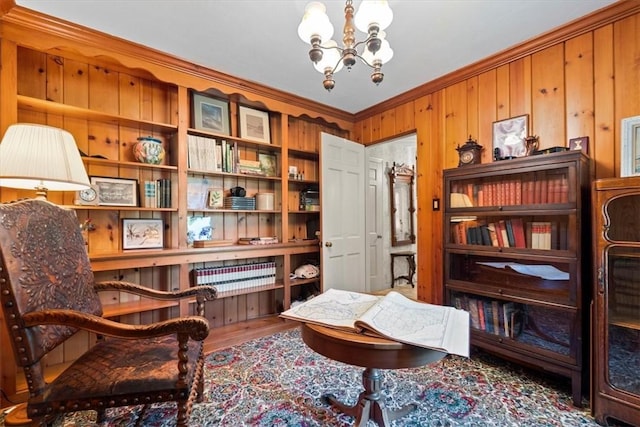 sitting room with wooden walls, hardwood / wood-style flooring, ornamental molding, and a notable chandelier