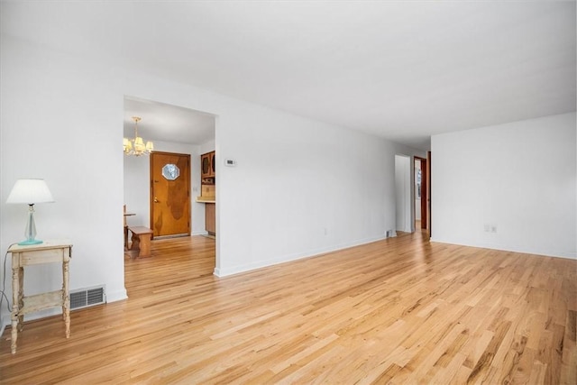 spare room with light wood-type flooring and an inviting chandelier