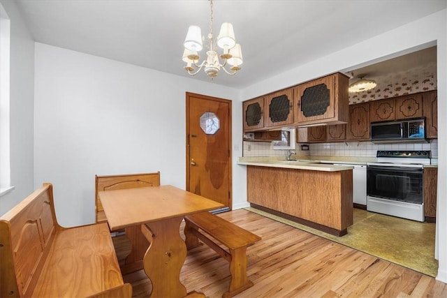 kitchen featuring kitchen peninsula, hanging light fixtures, light wood-type flooring, and white electric stove